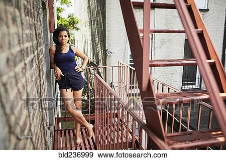 Portrait of smiling woman standing on urban fire escape View Large Photo Image Stock Photo - Portrait of smiling woman standing on urban fire escape. Fotosearch