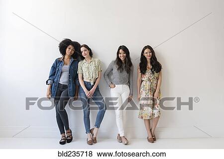 Stock Photo - Portrait of smiling women leaning on wall. Fotosearch