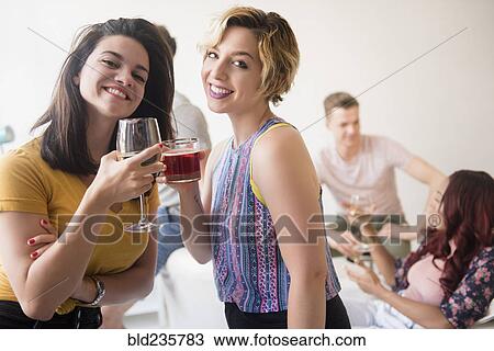 Stock Image - Portrait of smiling women toasting at party. Fotosearch