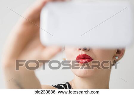 Stock Photograph - Red lips of woman posing for cell phone selfie. Fotosearch