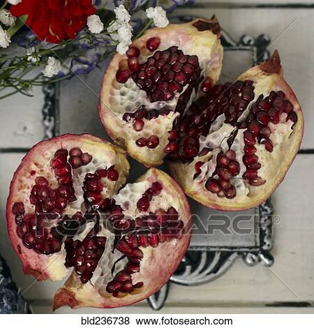 Red seeds in sliced pomegranate near flowers View Large Photo Image Stock Photo - Red seeds in sliced pomegranate near flowers. Fotosearch