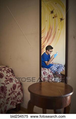 Reflection in mirror of Hispanic boy reading book on bed View Large Photo Image Stock Photography - Reflection in mirror of Hispanic boy reading book on bed. Fotosearch