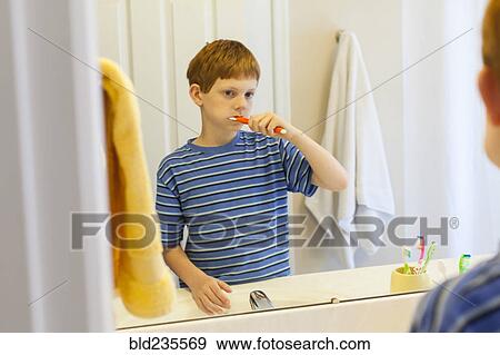 Stock Photo - Reflection of Caucasian boy brushing teeth in mirror. Fotosearch