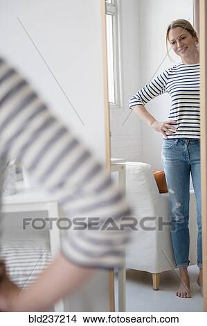 Picture - Reflection of standing Caucasian woman in mirror. Fotosearch
