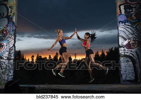 Stock Photography - Runners jumping and high-fiving. Fotosearch
