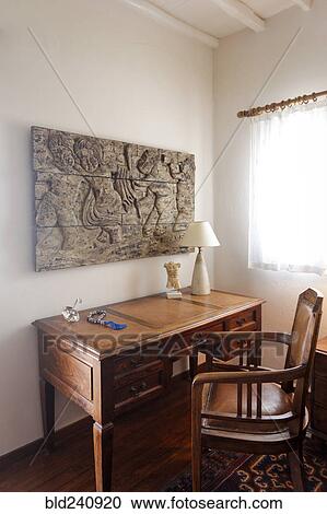 Sculpture on wall above desk and chair View Large Photo Image Stock Image - Sculpture on wall above desk and chair. Fotosearch