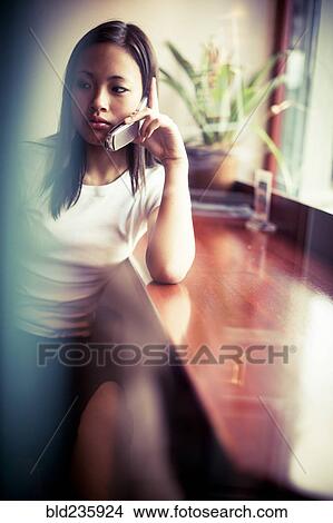 Picture - Serious Asian girl talking on cell phone. Fotosearch