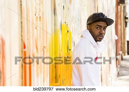 Serious Black man standing near gate View Large Photo Image Stock Photo - Serious Black man standing near gate. Fotosearch