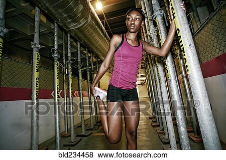 Stock Photo - Serious Black woman holding pole and stretching leg. Fotosearch