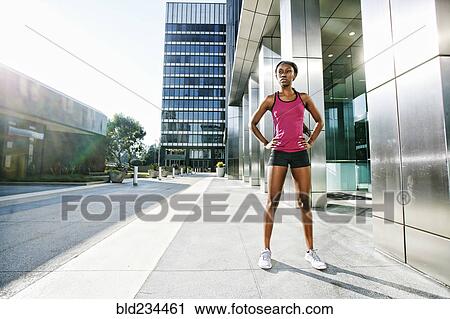 Stock Image - Serious Black woman standing on city sidewalk. Fotosearch