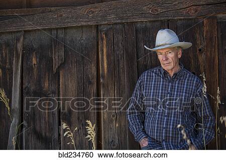 Serious Caucasian farmer leaning on wooden fence View Large Photo Image Stock Image - Serious Caucasian farmer leaning on wooden fence. Fotosearch