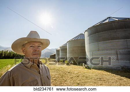 Serious Caucasian farmer near storage silos View Large Photo Image Stock Image - Serious Caucasian farmer near storage silos. Fotosearch