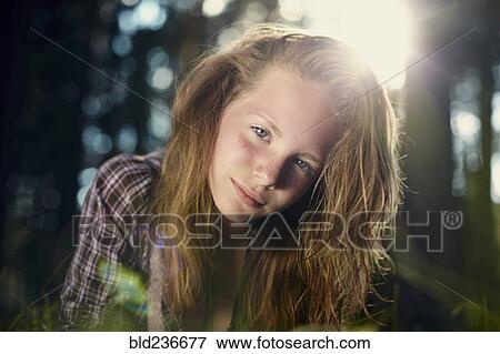 Stock Photo - Serious Caucasian girl in sunny forest. Fotosearch