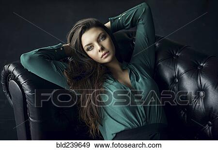 Stock Photo - Serious Caucasian woman relaxing on sofa. Fotosearch