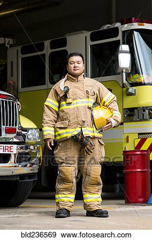 Stock Photo - Serious Chinese fireman posing near fire trucks. Fotosearch
