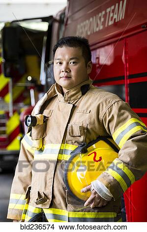 Serious Chinese fireman standing near fire truck View Large Photo Image Picture - Serious Chinese fireman standing near fire truck. Fotosearch