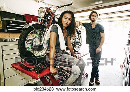Serious man and woman posing with motorcycle in garage View Large Photo Image Stock Image - Serious man and woman posing with motorcycle in garage. Fotosearch