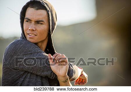Serious Mixed Race man stretching arms View Large Photo Image Stock Photo - Serious Mixed Race man stretching arms. Fotosearch