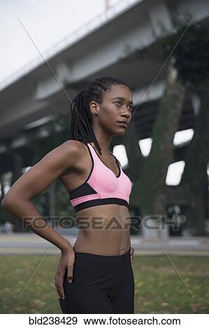 Serious Mixed Race woman wearing pink sports-bra near bridge View Large Photo Image Stock Photo - Serious Mixed Race woman wearing pink sports-bra near bridge. Fotosearch