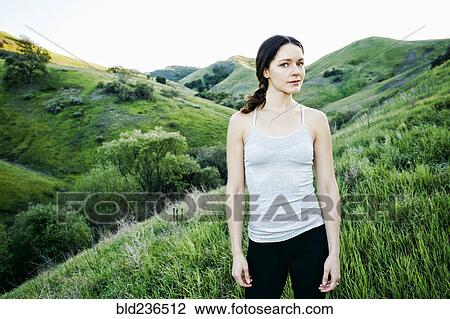 Stock Image - Serious woman standing on hill. Fotosearch