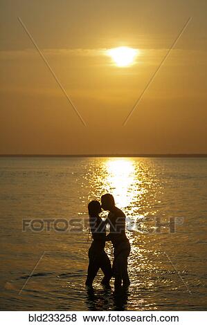 Silhouette of Caucasian couple kissing in ocean at sunset View Large Photo Image Stock Photo - Silhouette of Caucasian couple kissing in ocean at sunset. Fotosearch