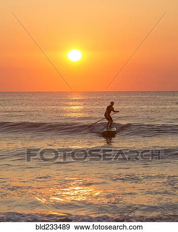 Silhouette of man paddleboarding on ocean waves View Large Photo Image Stock Photo - Silhouette of man paddleboarding on ocean waves. Fotosearch