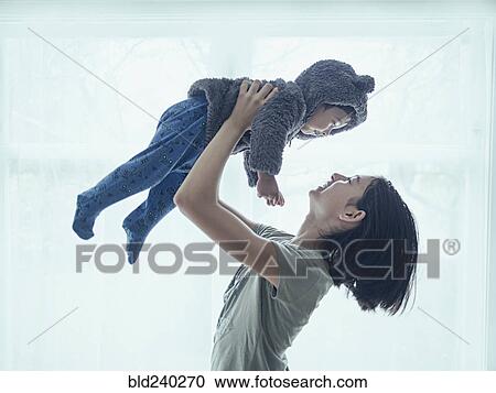 Stock Image - Sister lifting baby brother. Fotosearch