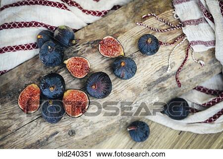 Stock Image - Sliced figs on wooden log. Fotosearch