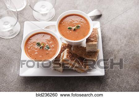 Stock Image - Sliced grilled cheese sandwich and tomato soup. Fotosearch