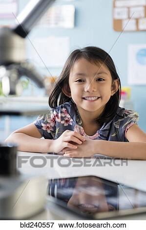 Smiling Asian girl leaning posing at desk View Large Photo Image Stock Photo - Smiling Asian girl leaning posing at desk. Fotosearch
