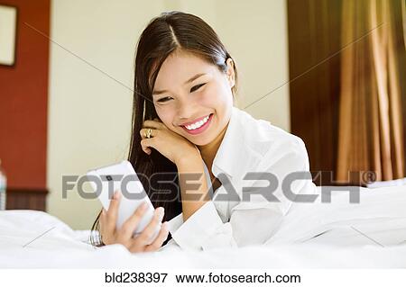 Smiling Asian teenage girl texting on cell phone View Large Photo Image Stock Photo - Smiling Asian teenage girl texting on cell phone. Fotosearch