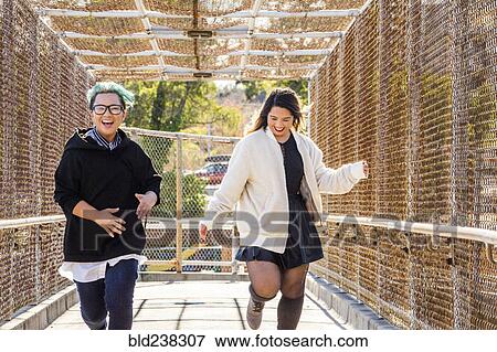 Smiling Asian women running on footbridge View Large Photo Image Stock Photo - Smiling Asian women running on footbridge. Fotosearch