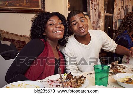 Stock Image - Smiling Black brother and sister at dinner table. Fotosearch