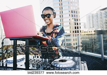 Stock Photo - Smiling Black DJ on urban rooftop. Fotosearch