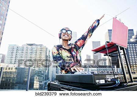 Stock Photo - Smiling Black DJ on urban rooftop. Fotosearch