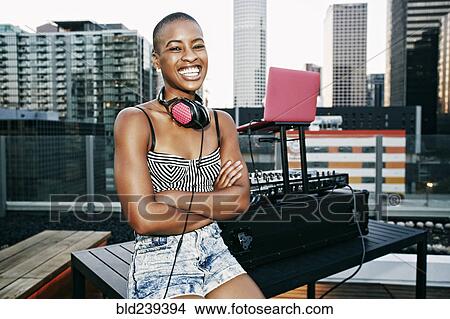 Picture - Smiling Black DJ relaxing on urban rooftop. Fotosearch