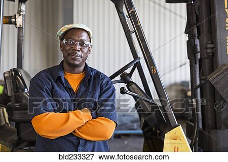 Smiling Black worker posing near forklift in factory View Large Photo Image Stock Photo - Smiling Black worker posing near forklift in factory. Fotosearch