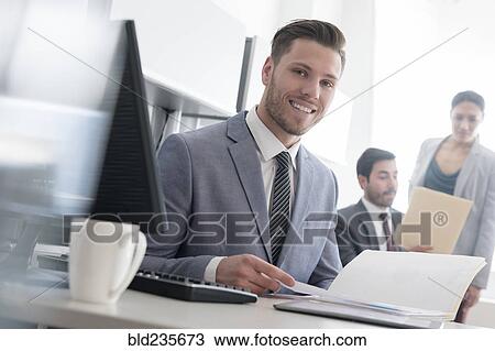 Smiling businessman reading file in office View Large Photo Image Stock Image - Smiling businessman reading file in office. Fotosearch