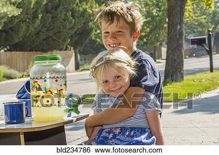 Stock Photograph - Smiling Caucasian boy hugging girl and selling lemonade. Fotosearch