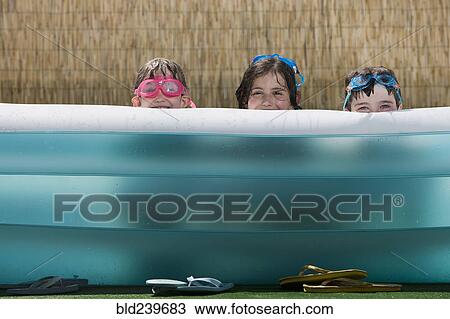 Smiling Caucasian children hiding in inflatable swimming pool View Large Photo Image Stock Image - Smiling Caucasian children hiding in inflatable swimming pool. Fotosearch
