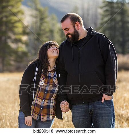 Smiling Caucasian couple holding hands in field View Large Photo Image Stock Photo - Smiling Caucasian couple holding hands in field. Fotosearch