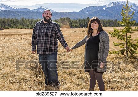 Smiling Caucasian couple holding hands in field View Large Photo Image Stock Photo - Smiling Caucasian couple holding hands in field. Fotosearch