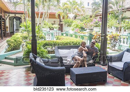 Smiling Caucasian couple on sofa in hotel courtyard View Large Photo Image Stock Image - Smiling Caucasian couple on sofa in hotel courtyard. Fotosearch