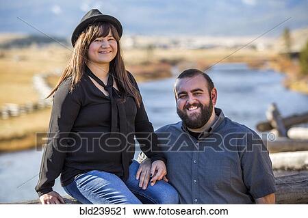 Stock Image - Smiling Caucasian couple posing near river. Fotosearch