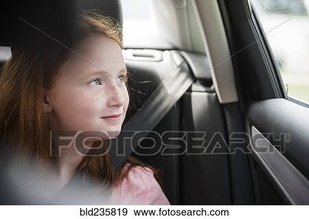 Stock Photo - Smiling Caucasian girl in car looking out window. Fotosearch