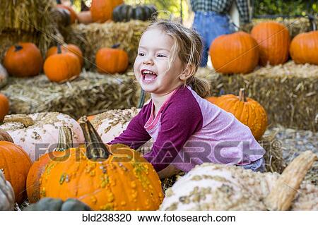 Smiling Caucasian girl playing in pumpkin patch View Large Photo Image Stock Image - Smiling Caucasian girl playing in pumpkin patch. Fotosearch