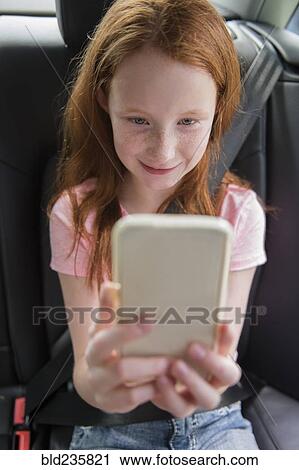 Smiling Caucasian girl texting on cell phone in car View Large Photo Image Stock Image - Smiling Caucasian girl texting on cell phone in car. Fotosearch