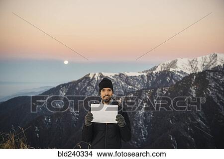 Smiling Caucasian man holding blank sign in mountain landscape View Large Photo Image Picture - Smiling Caucasian man holding blank sign in mountain landscape. Fotosearch