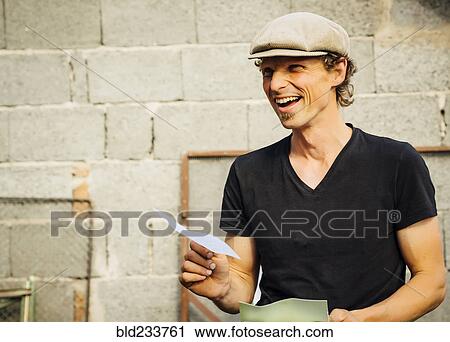 Stock Image - Smiling Caucasian man holding paper. Fotosearch