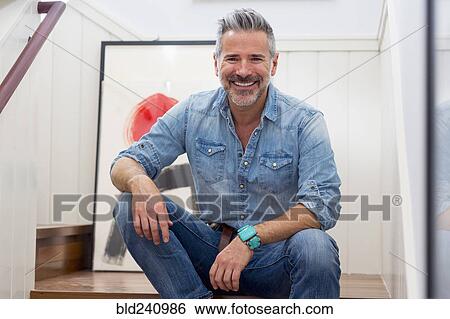Stock Photograph - Smiling Caucasian man sitting on staircase. Fotosearch